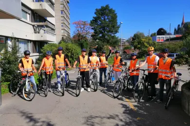 Eine Gruppe Flüchtlinge posiert mit Velos. Sie tragen Leuchtwesten und Velohelme.