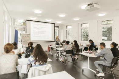Schüler des Lehrgangs Pflegehelfer sitzen in einem Schulzimmer.