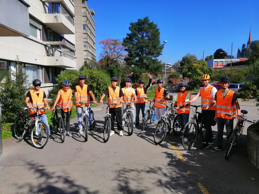 Eine Gruppe Flüchtlinge posiert mit Velos. Sie tragen Leuchtwesten und Velohelme.