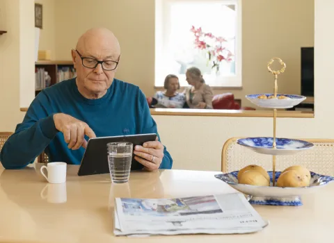 Mann mit Tablet am Küchentisch
